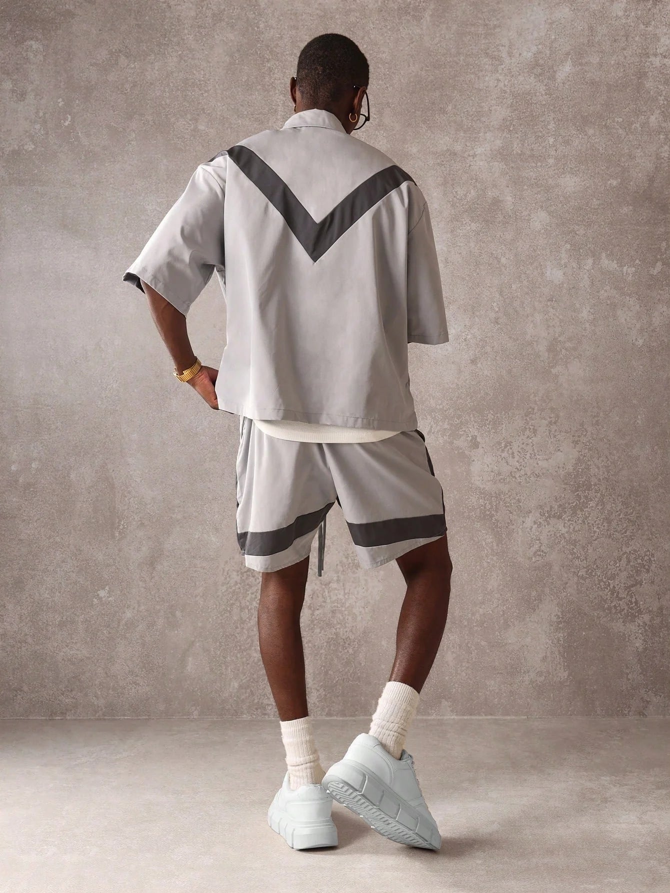 Person wearing a grey outfit with black accents against a plain background