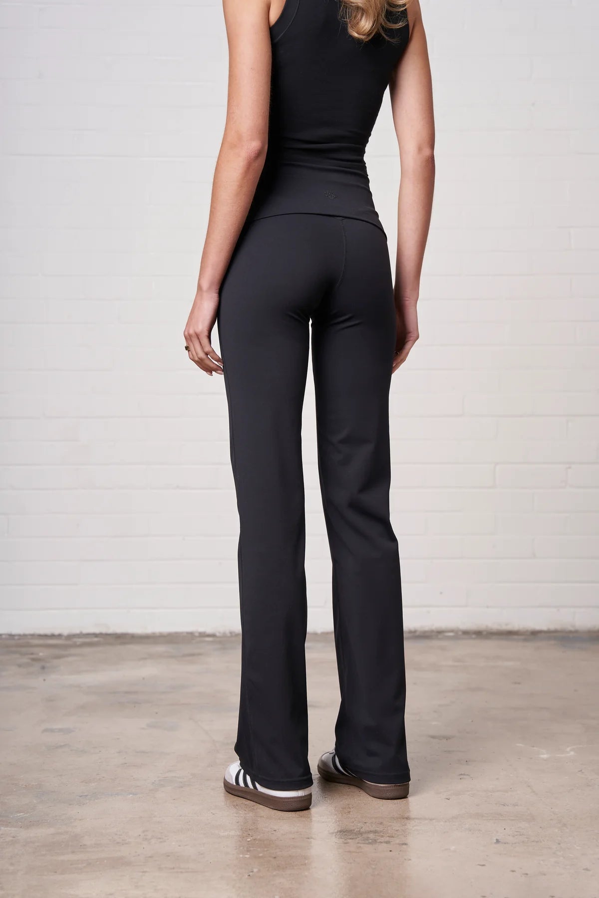 Person wearing black pants and a black top on a plain background
