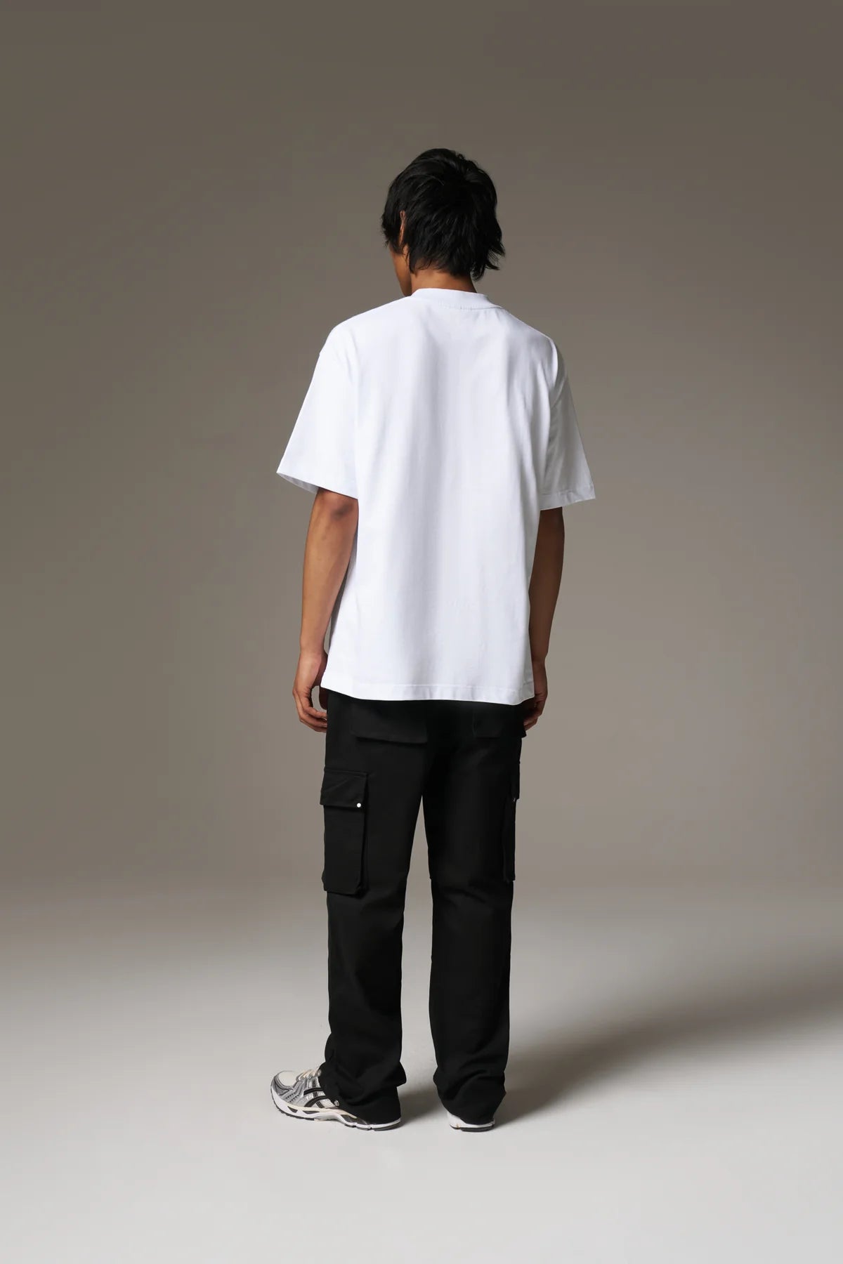 Person wearing a white t-shirt and black cargo pants on a plain background