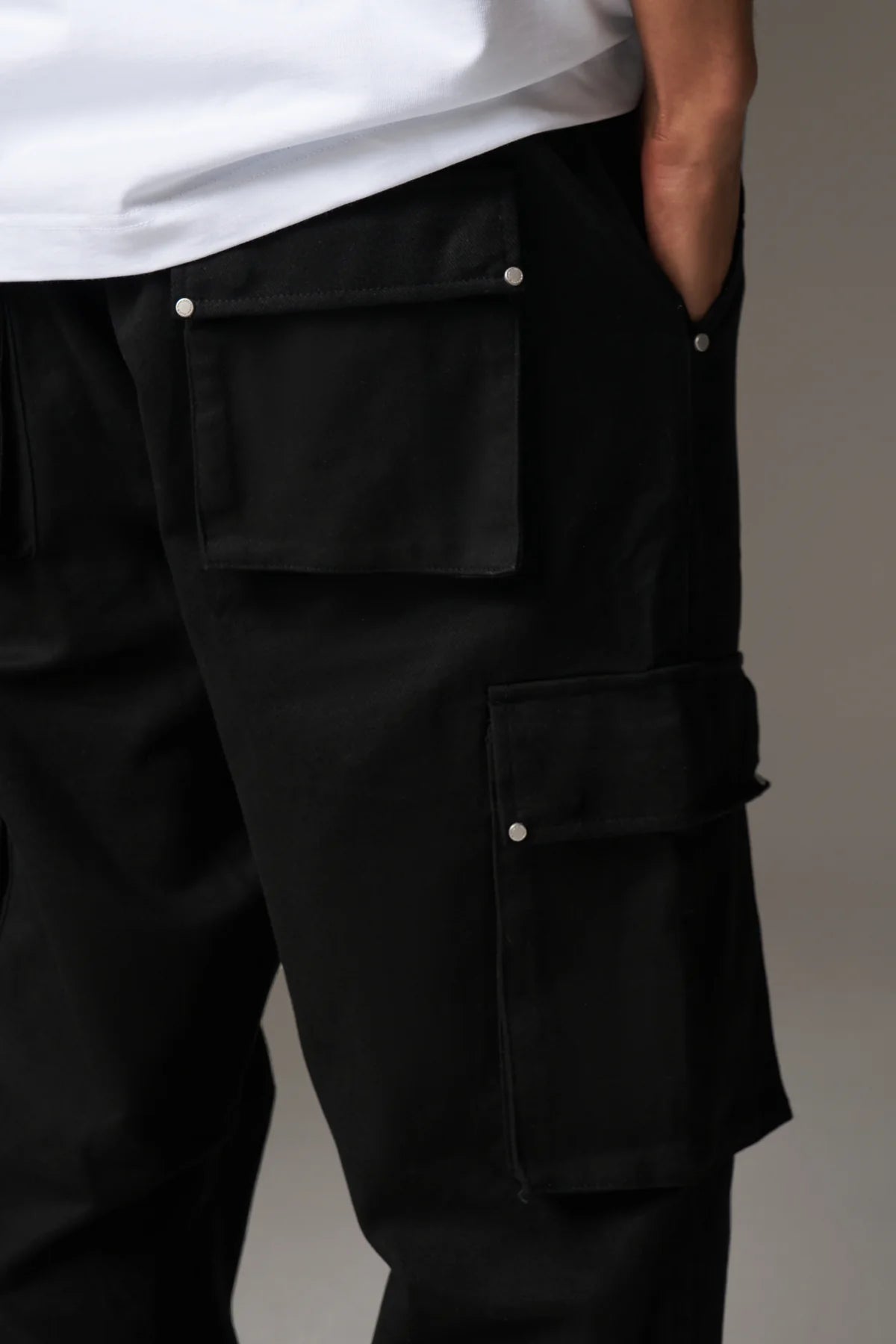 Black cargo pants with multiple pockets on a neutral background