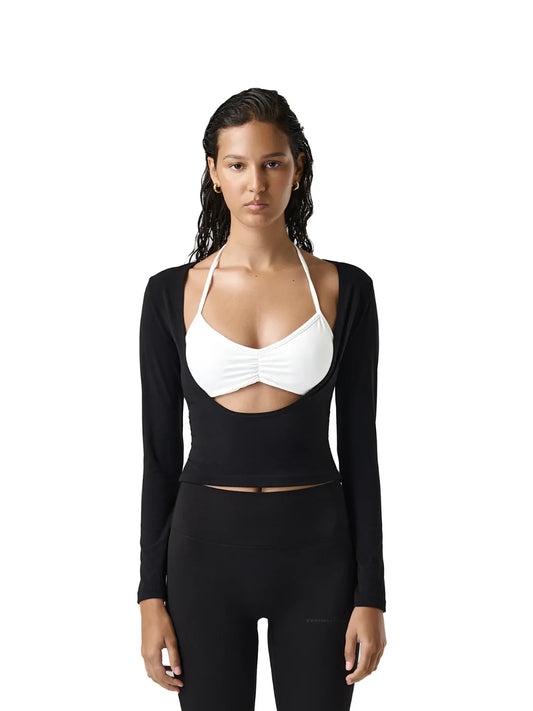 Woman wearing a black long-sleeve top and white halter top on a white background