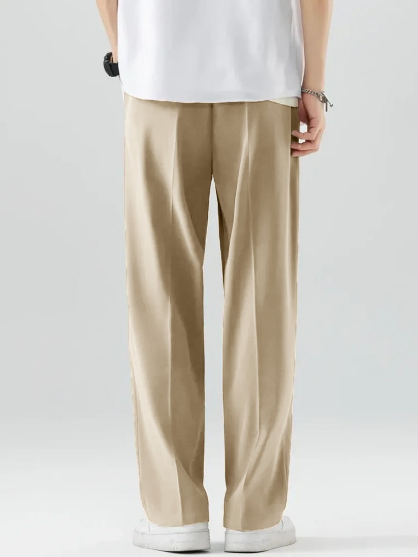 A person wearing Beige Tek Air loose fit pants and a white shirt, standing against a white background.