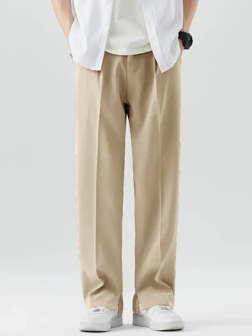 A person wearing Beige Tek Air loose fit pants and a white shirt, standing against a white background.
