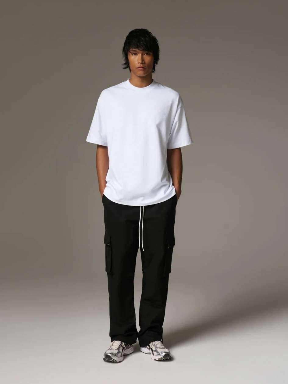Person wearing a white t-shirt and black cargo pants on a grey background