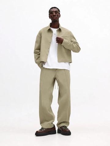 Man wearing a beige jacket and pants with a white shirt on a white background