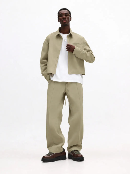 Man wearing a beige jacket and pants with a white shirt on a white background