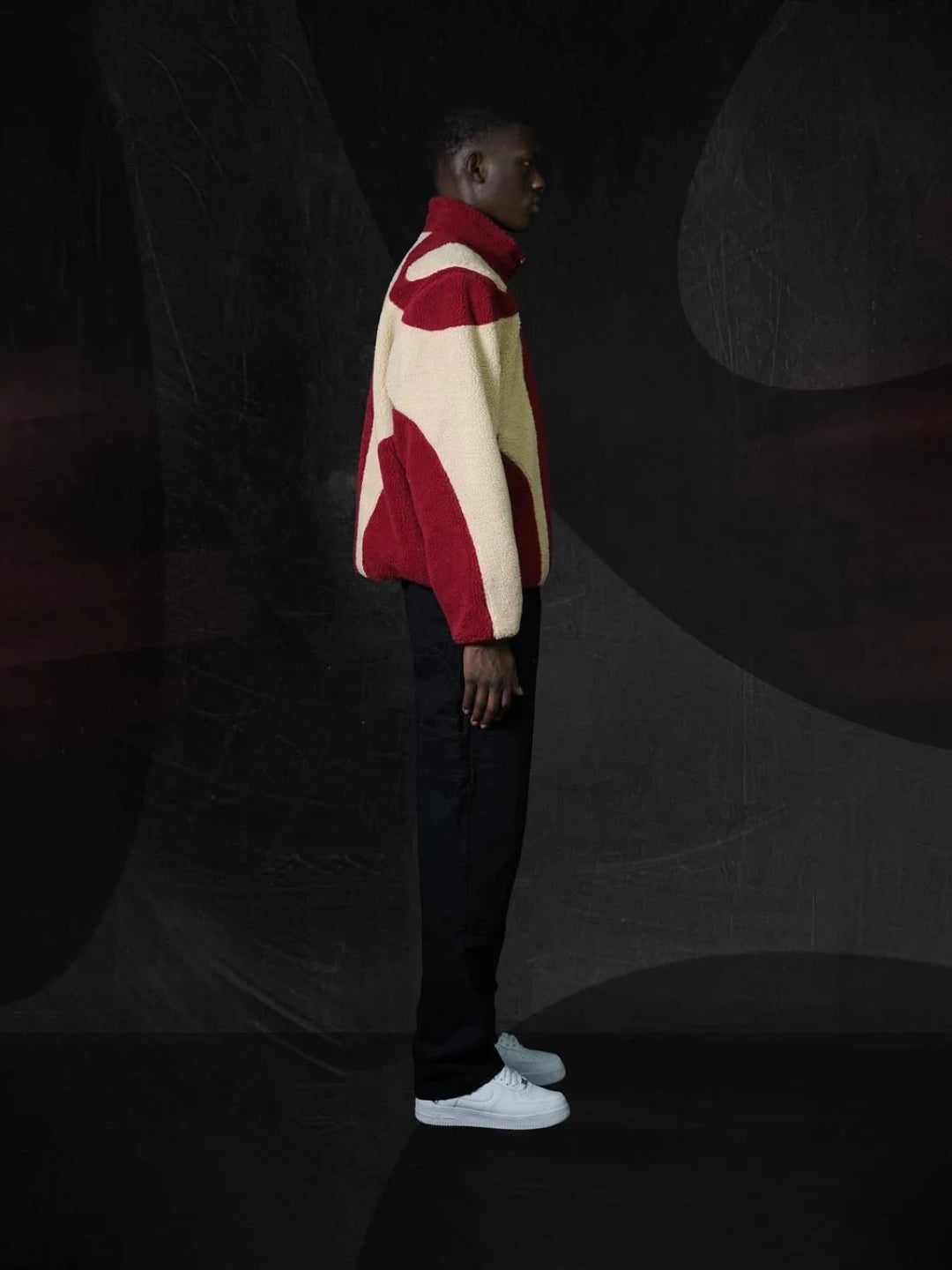 Person wearing a red and beige sweater against a dark background