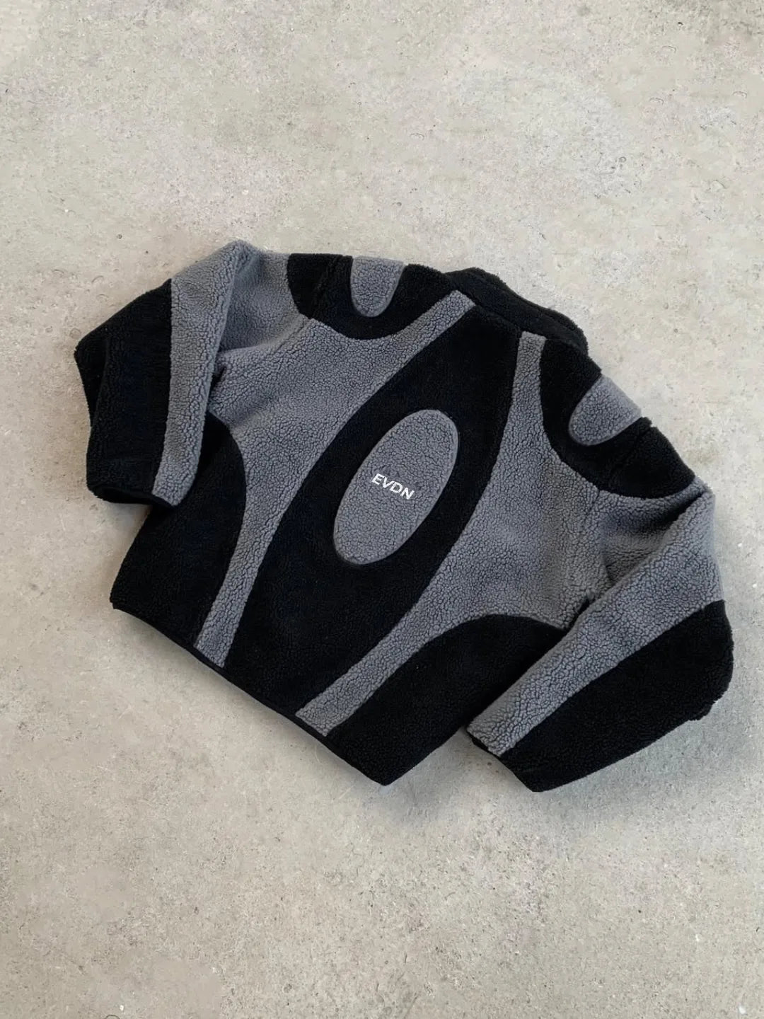 Black and gray sock with 'EVDN' branding on a beige surface