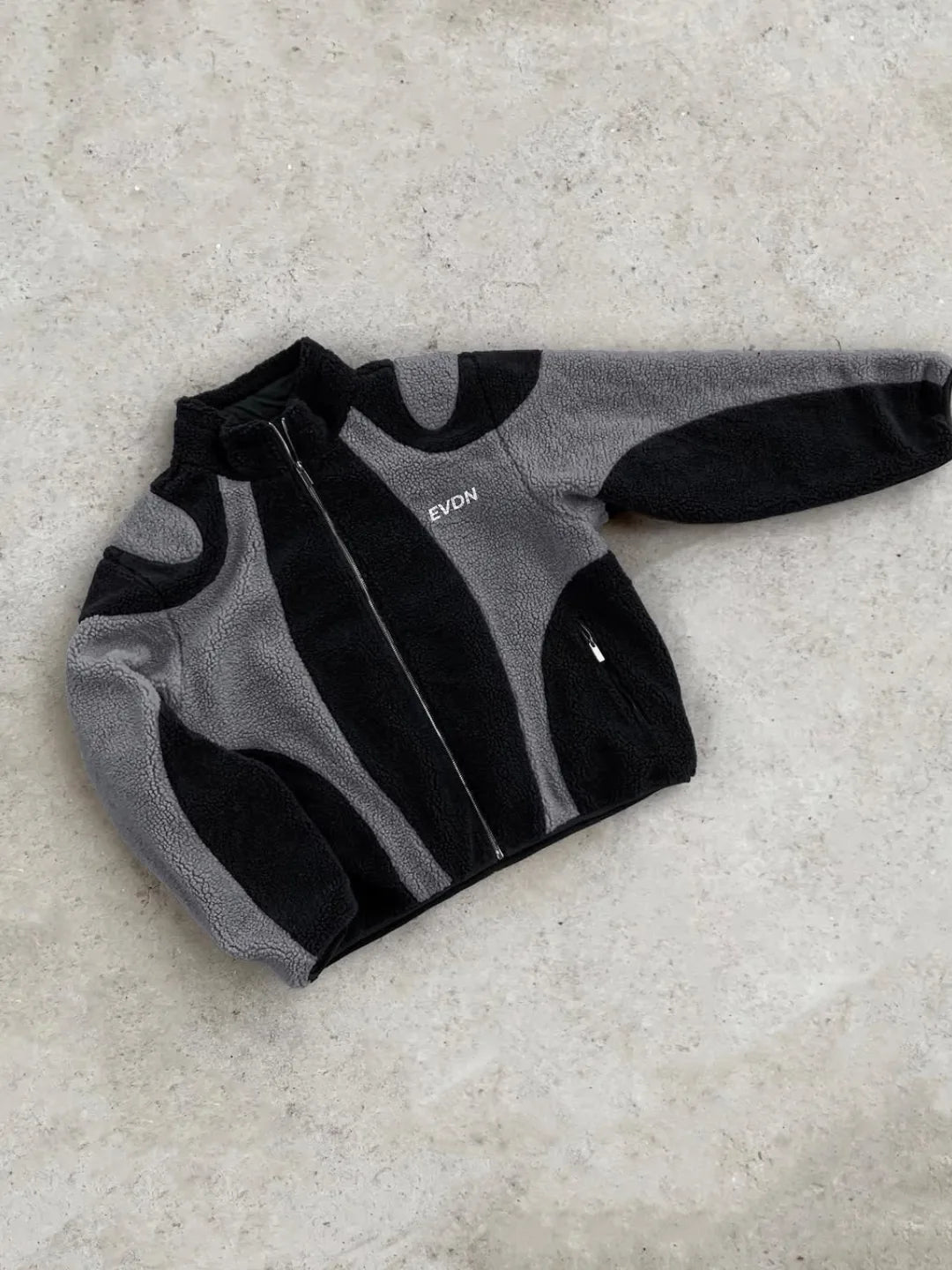 Gray and black fleece jacket with 'EVDN' branding on a light gray background