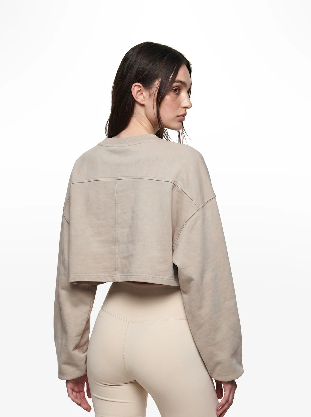 Woman wearing a beige cropped t-shirt and pants on a white background