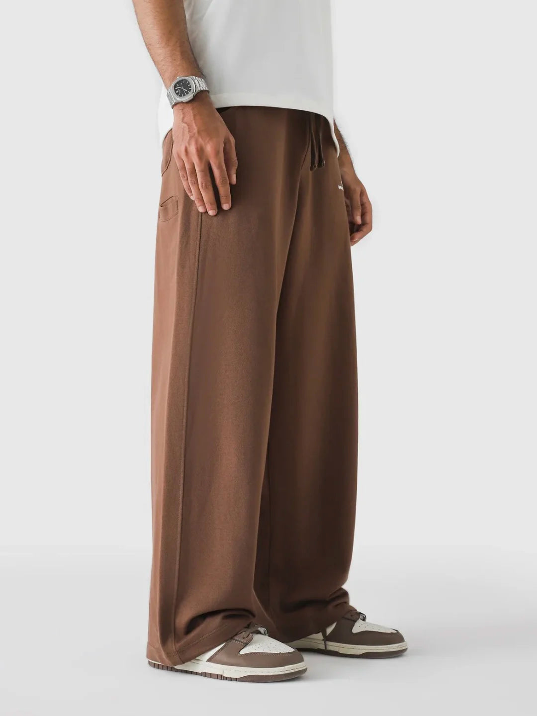 Person wearing brown wide-leg pants on a white background