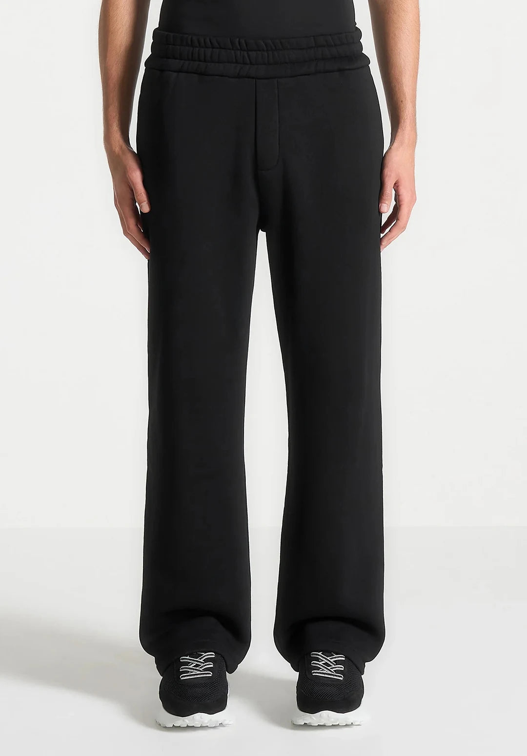 Black sweatpants worn by a person on a white background