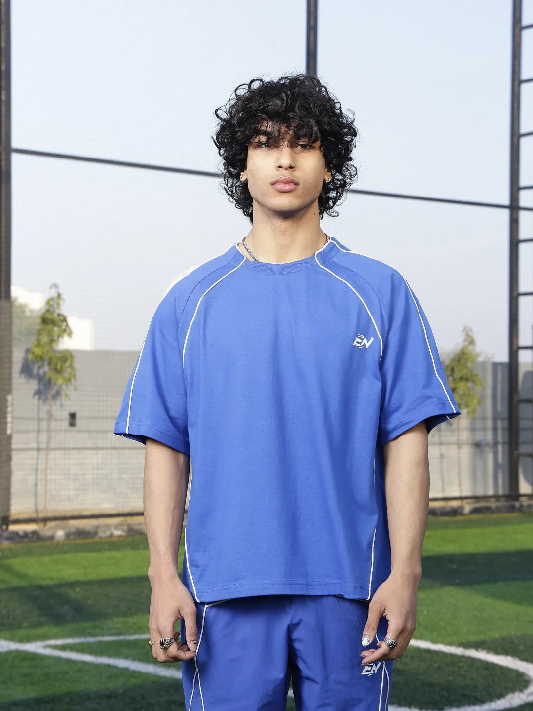 Person wearing a blue sports t-shirt with a logo on a sports field