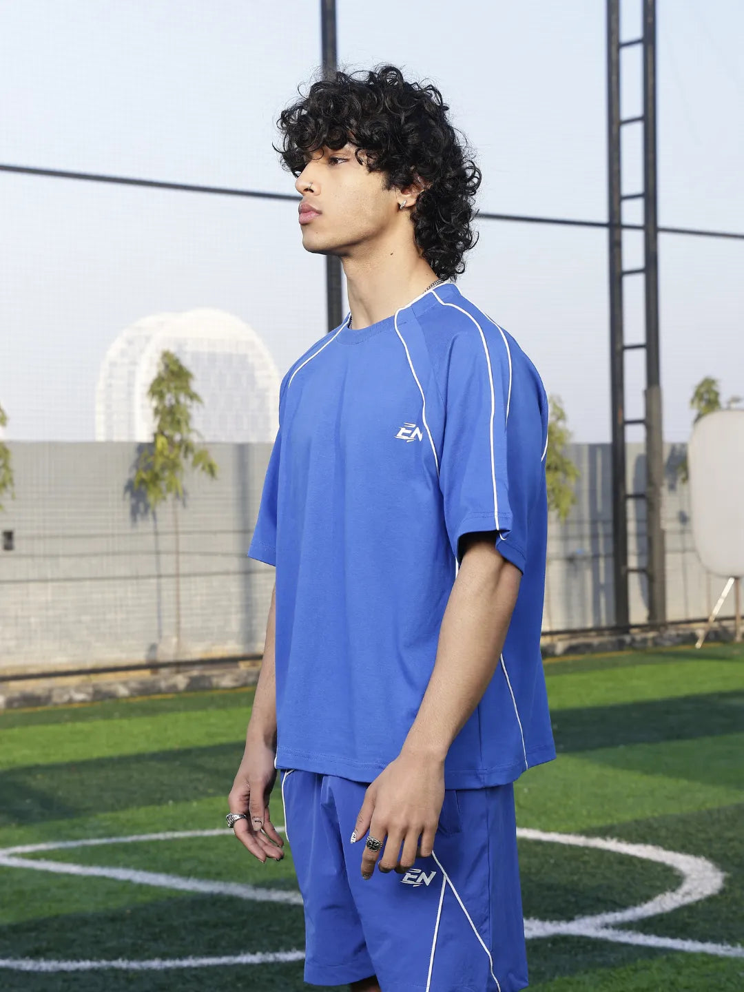 Person wearing a blue sports t-shirt with a logo on a sports field