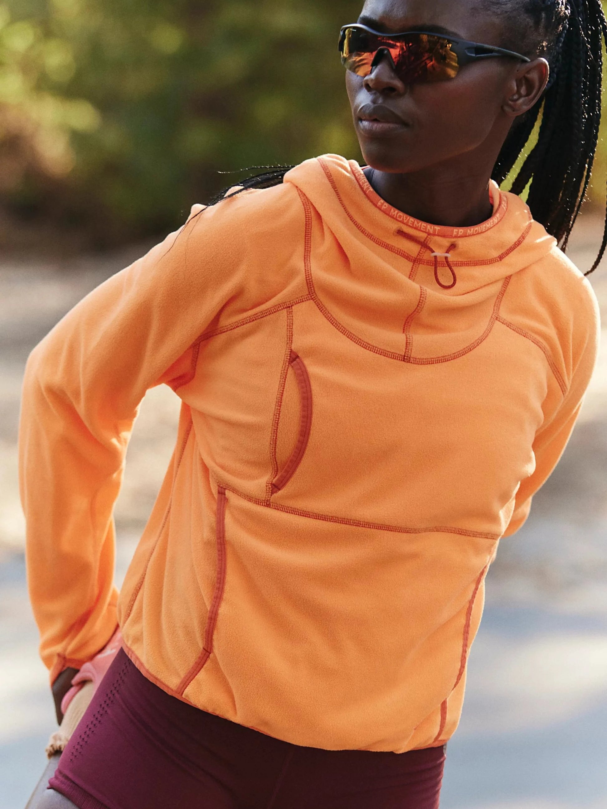Person wearing an orange jacket outdoors with a blurred natural background