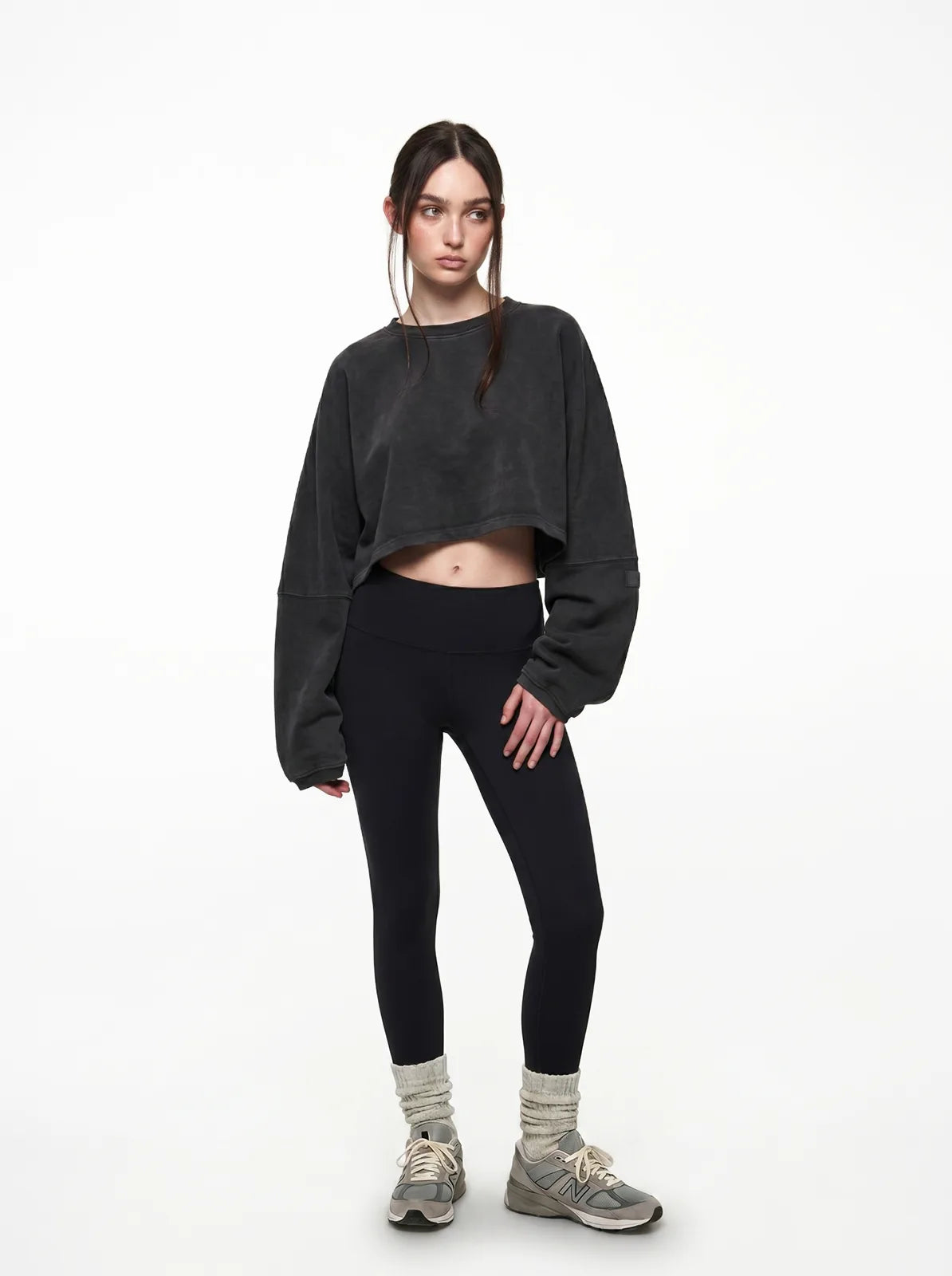 Person wearing a black cropped t-shirt and leggings on a white background
