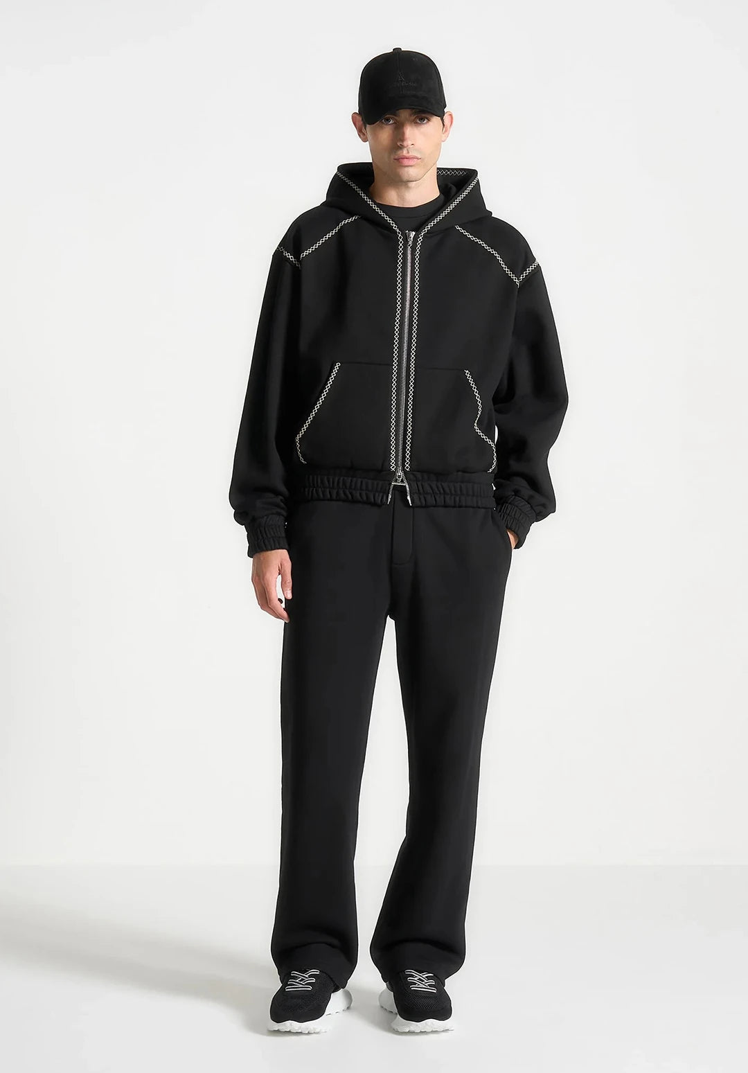 Person wearing a black tracksuit with white accents on a white background