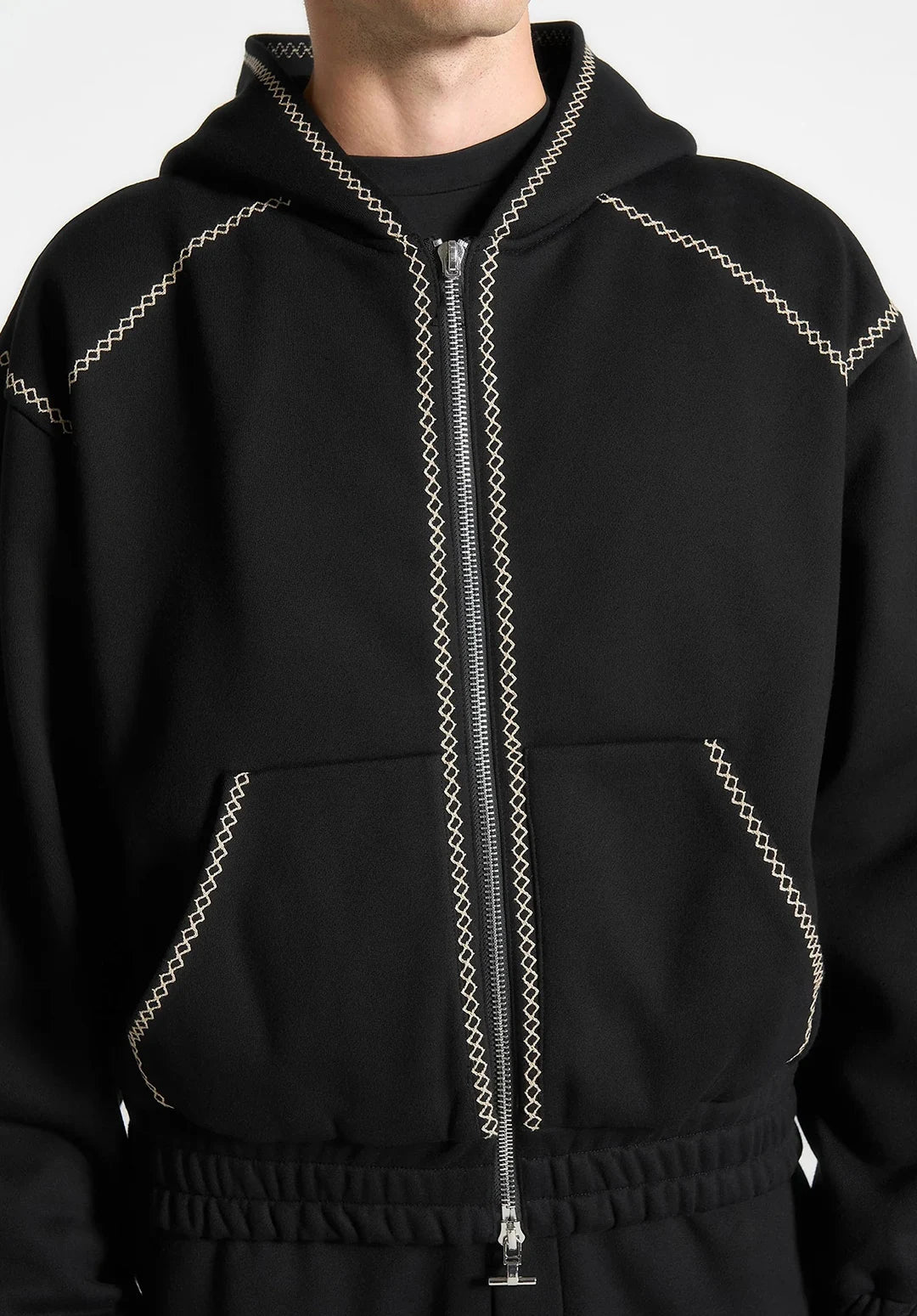 Black hoodie with decorative stitching on a neutral background