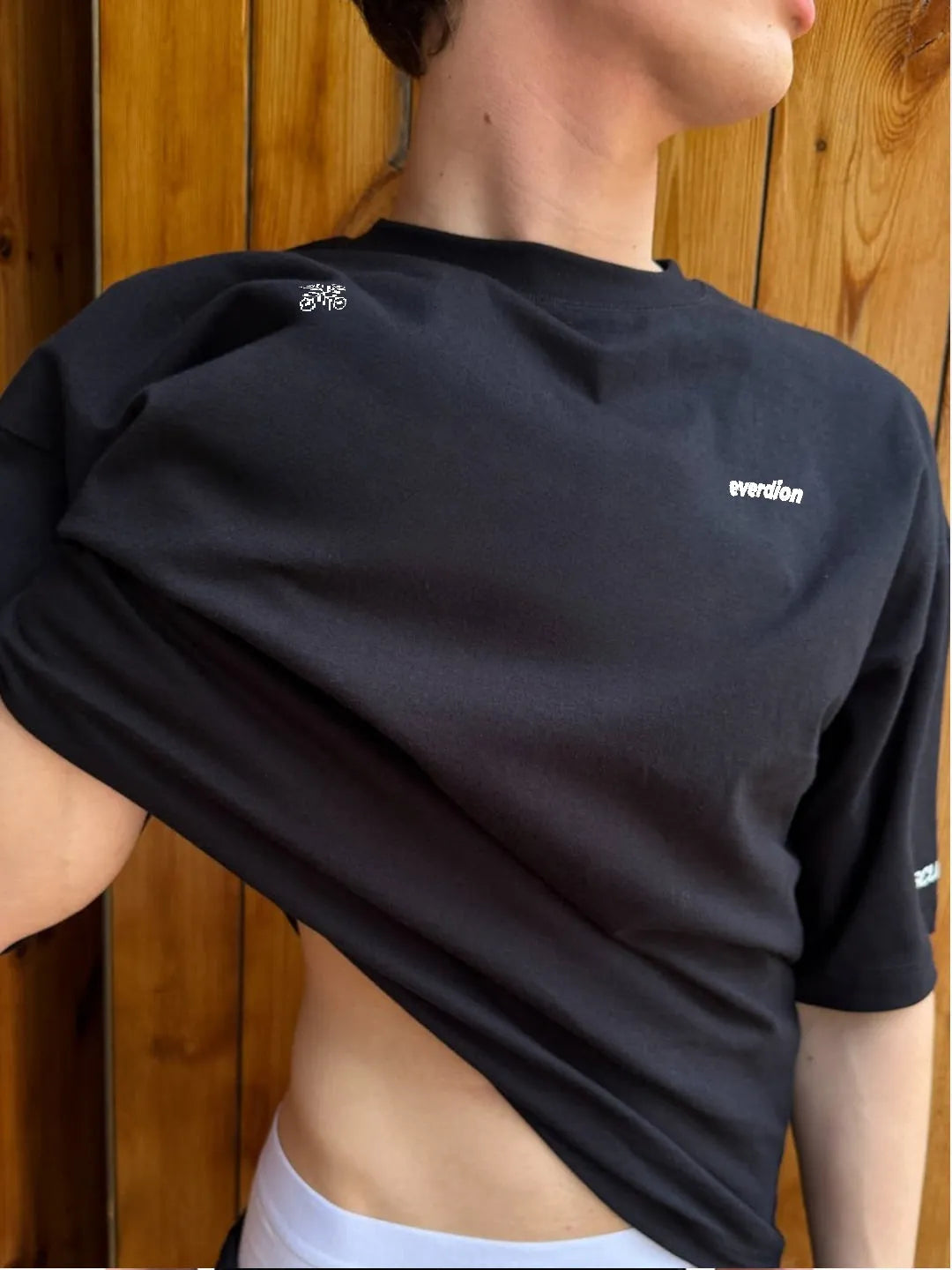 Person wearing a black athletic shirt with branding against a wooden background