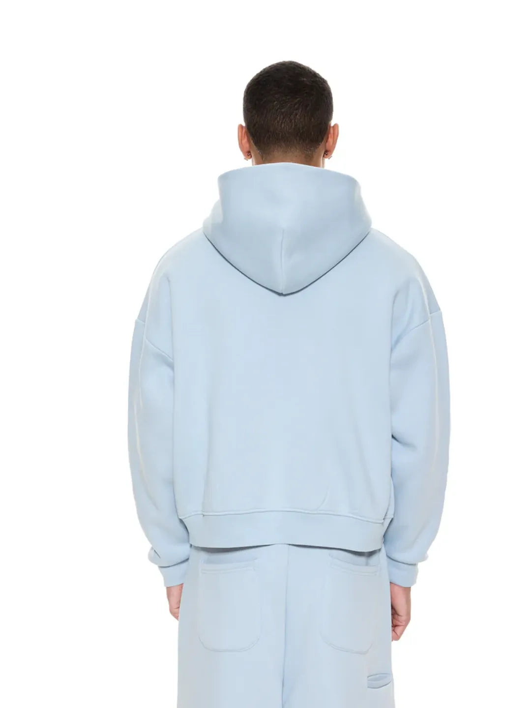 Person wearing a light blue zip-up jacket on a white background