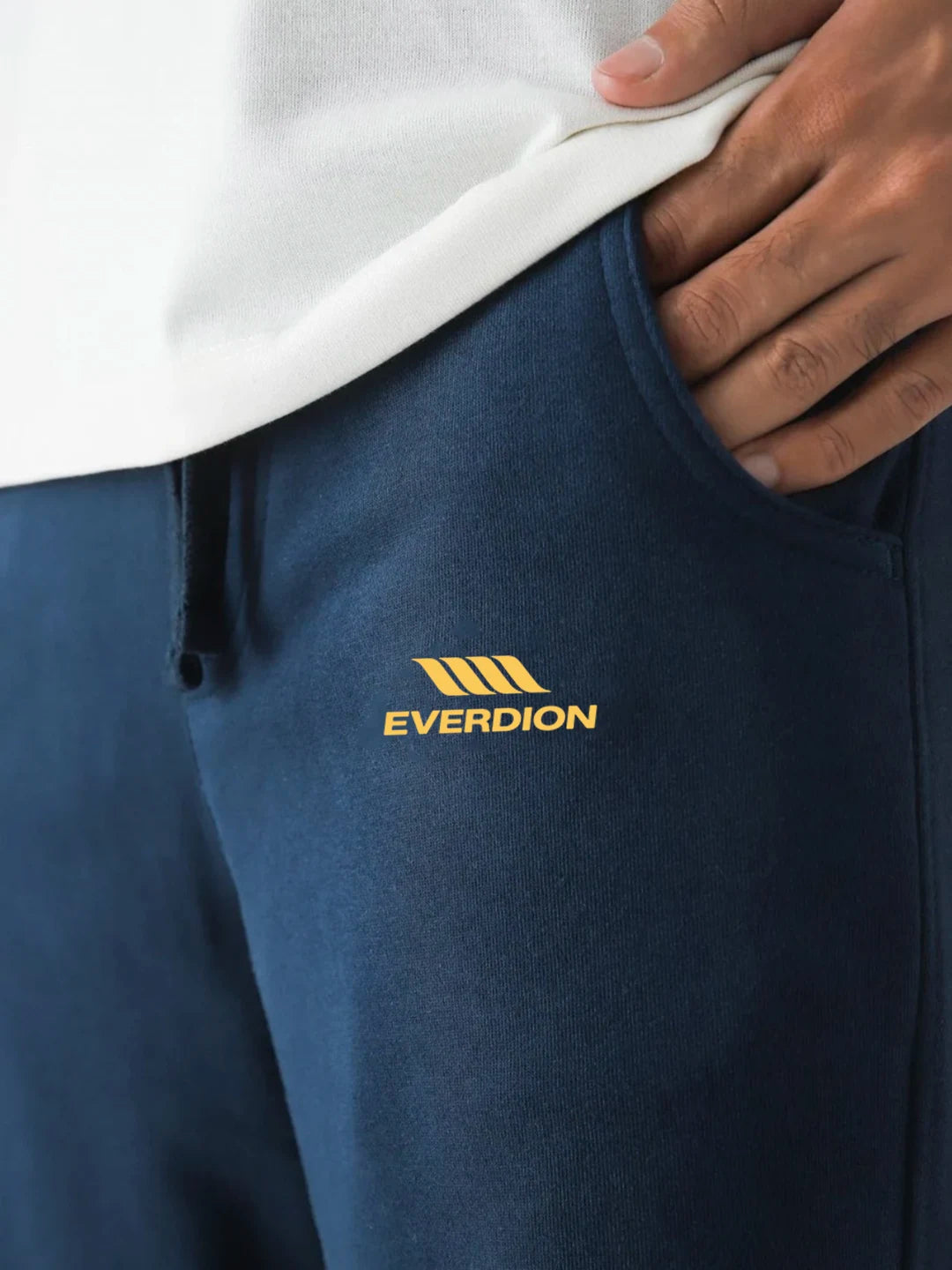 Blue pants with Everdion logo worn by a person, showing a close-up of the brand on the garment.