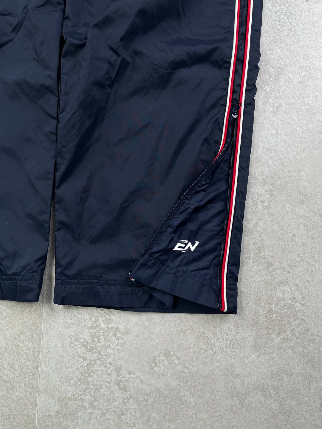 Navy blue jacket with a red and white stripe on a grey surface