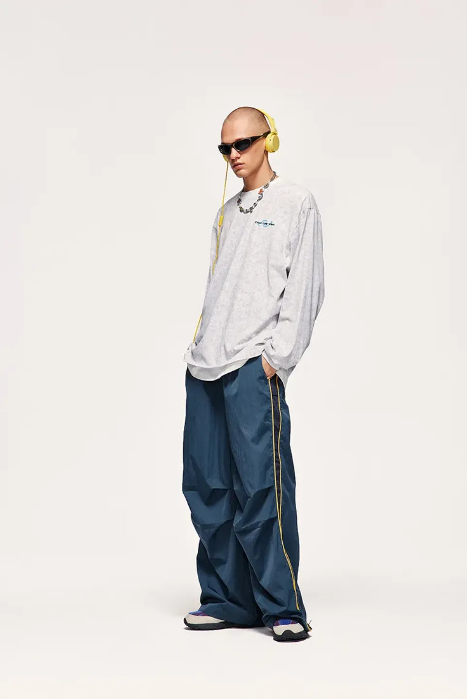 Person wearing a white shirt and blue pants with yellow headphones on a white background