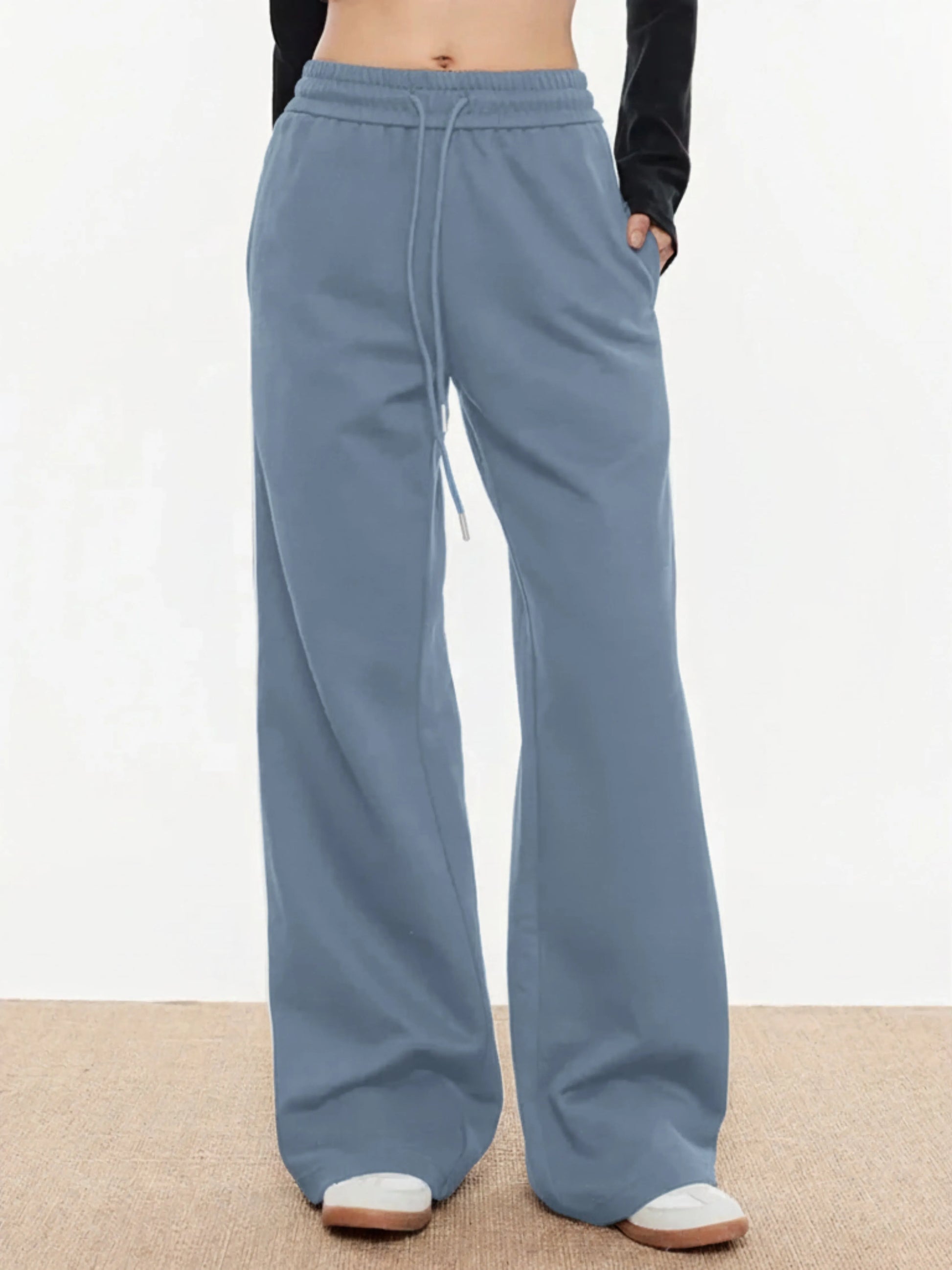 Blue trackpants worn by a person on a neutral background