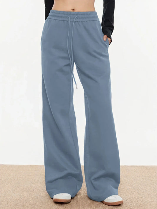 Blue trackpants worn by a person on a neutral background