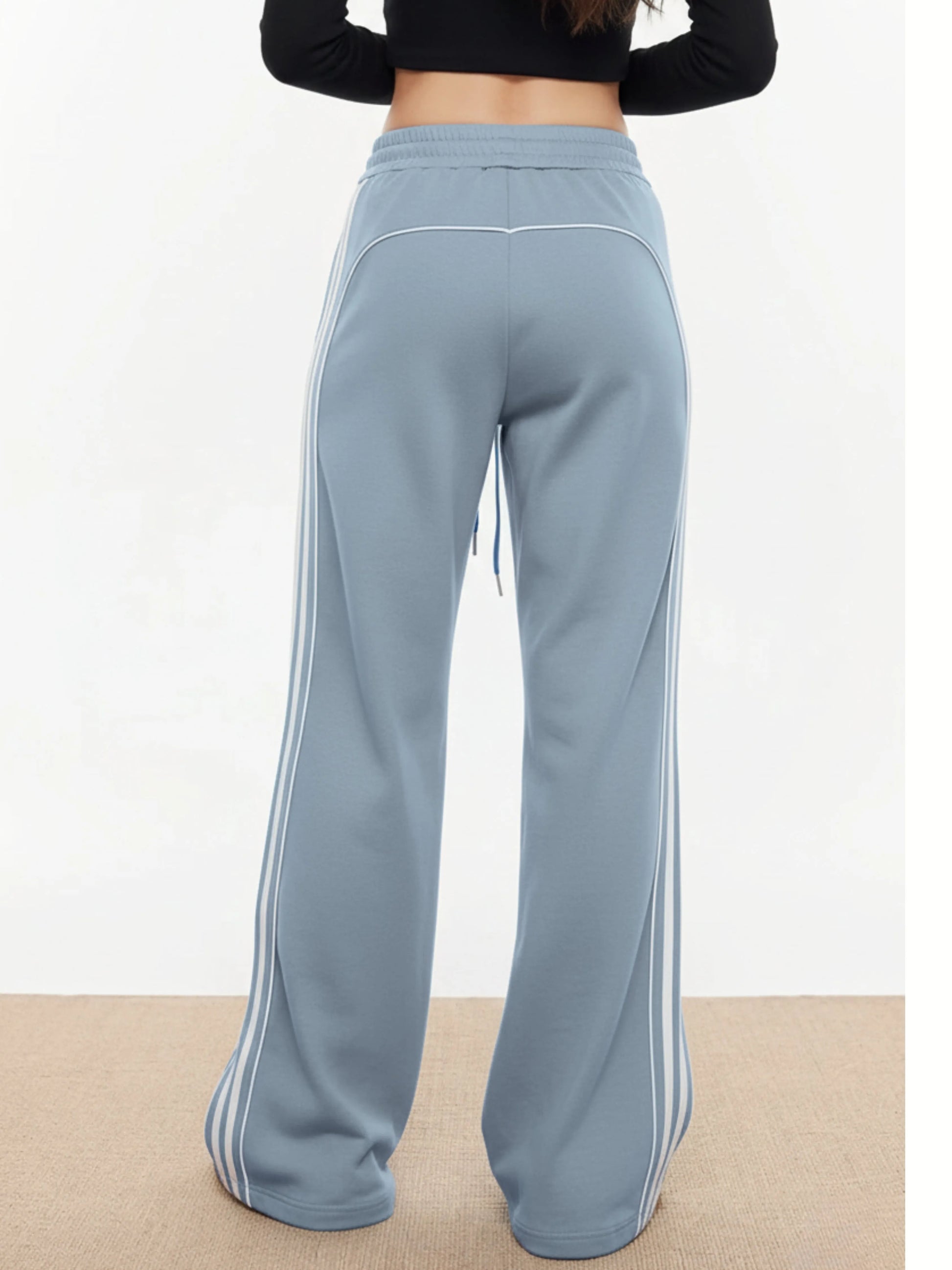 Light blue trackpants with white stripes on a plain background