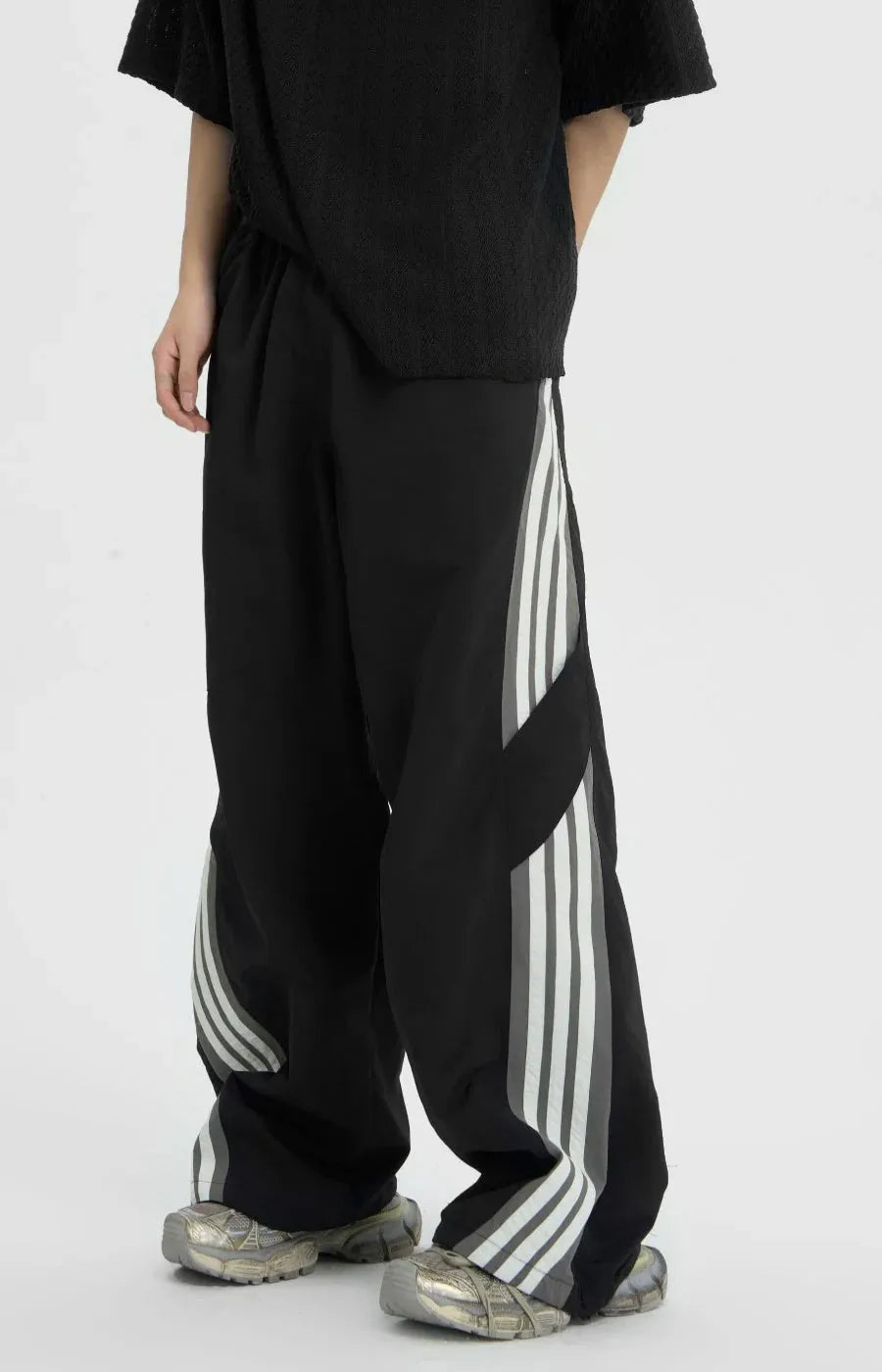 Person wearing black pants with white stripes on a white background