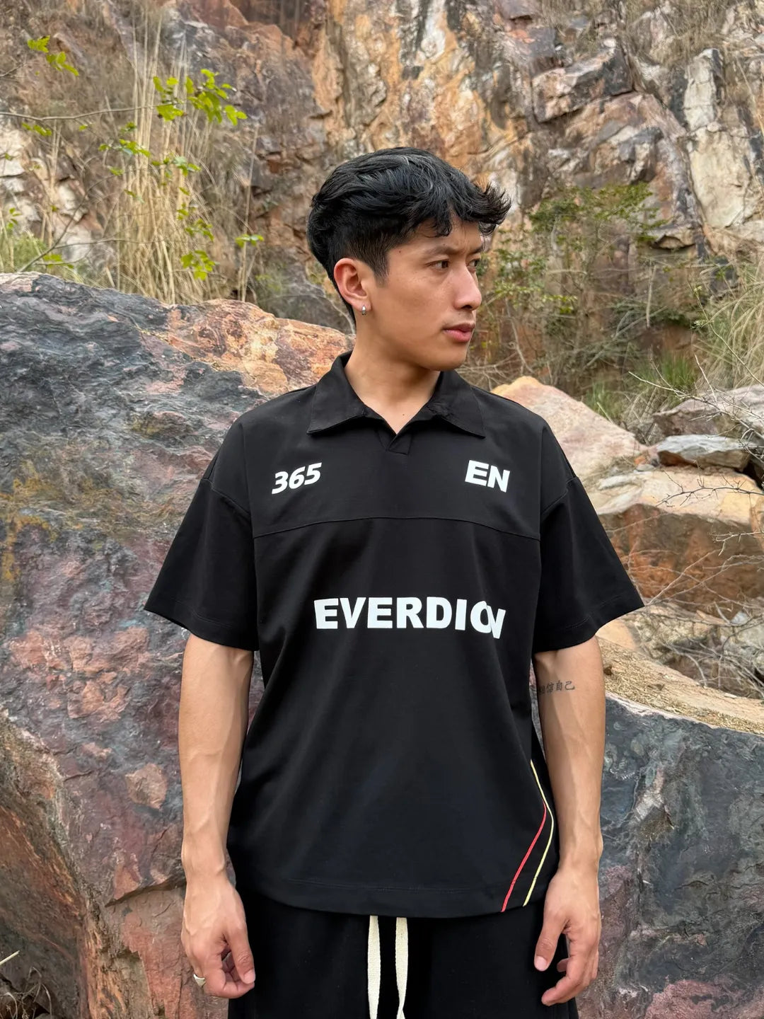 Person wearing a black 'EVERDION' shirt standing in a rocky outdoor setting