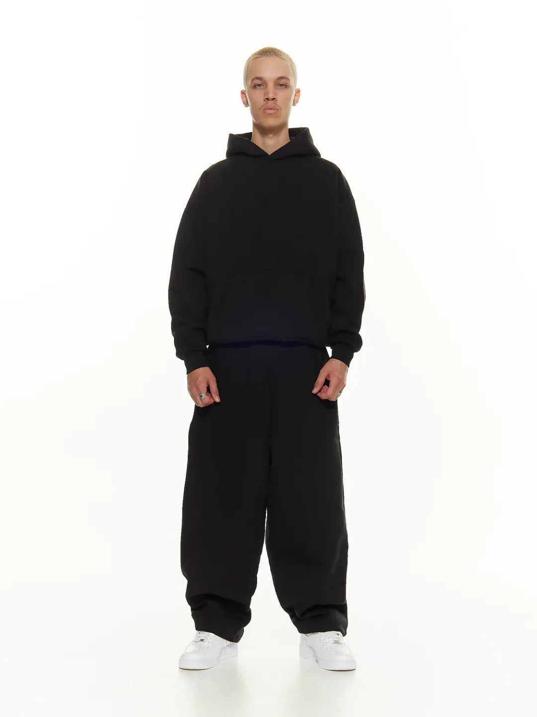 Person wearing a black hoodie and pants on a white background