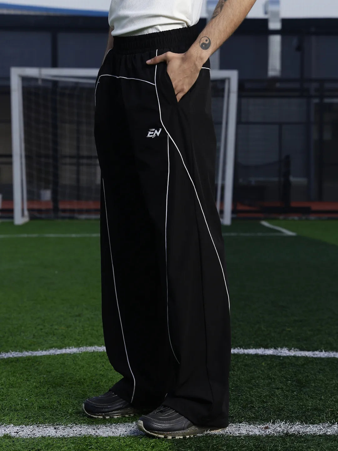 Person wearing black pants with a white line on a sports field