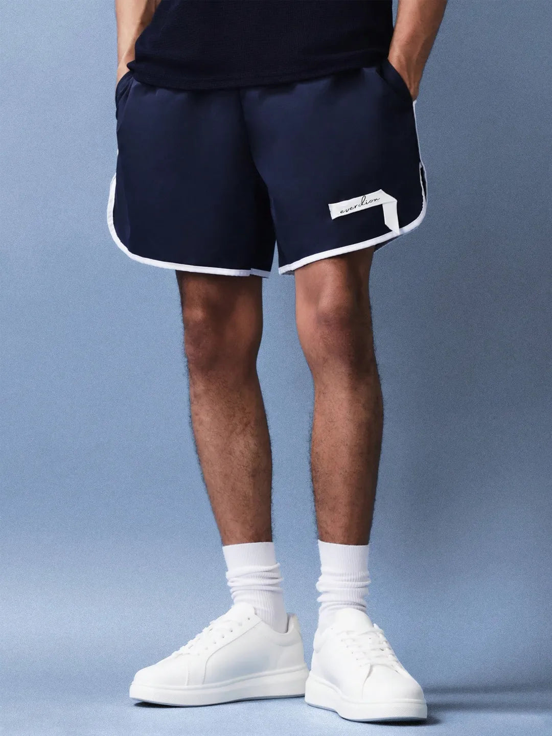 Person wearing navy shorts with a brand logo on a blue background