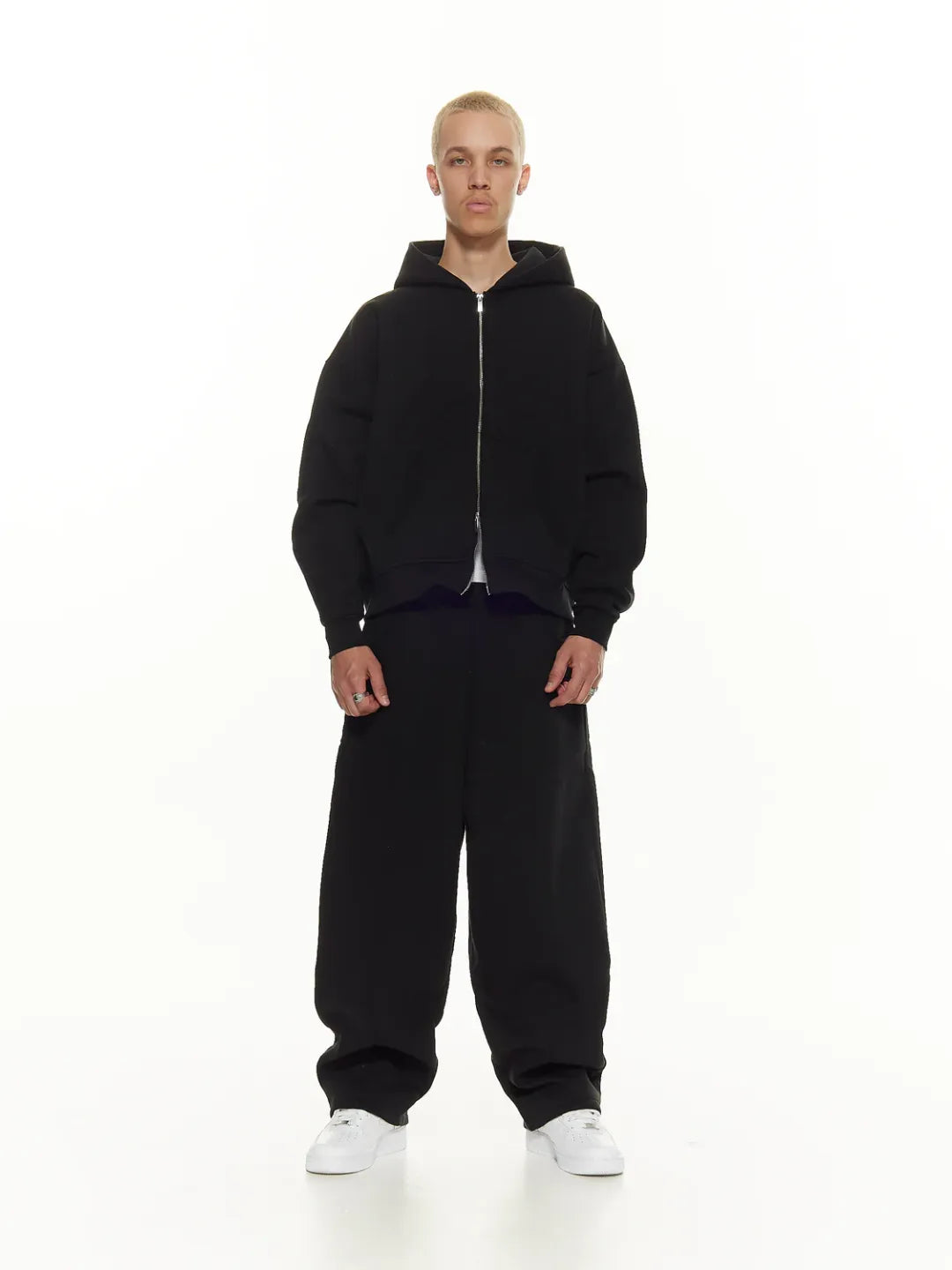 Person wearing a black zip-up jacket on a white background