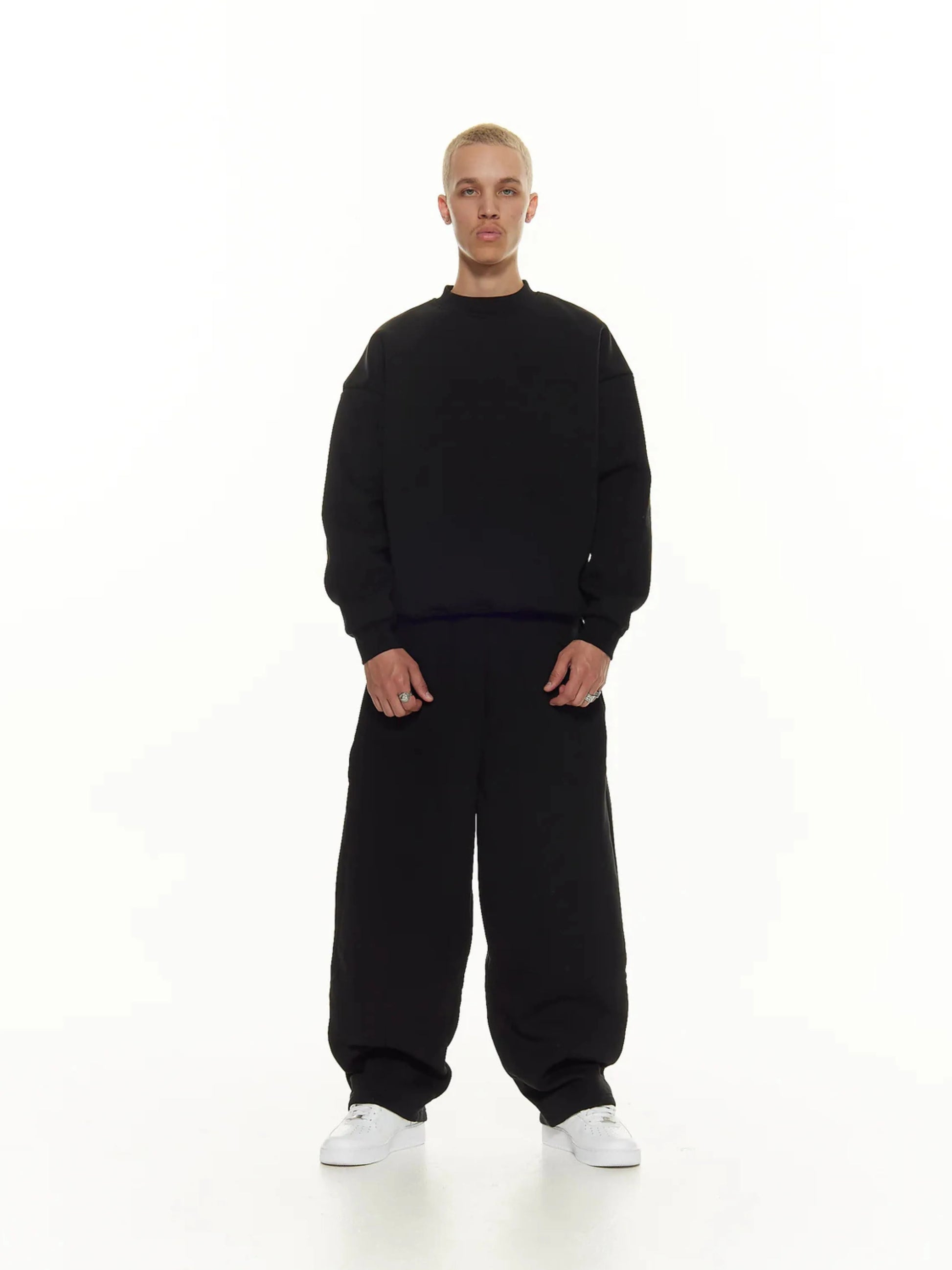 Person wearing a black sweatshirt and sweatpants set on a white background