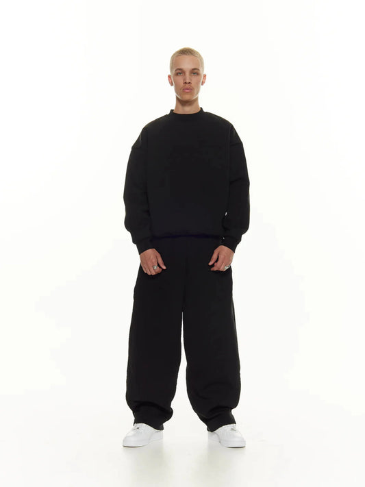 Person wearing a black sweatshirt and sweatpants set on a white background