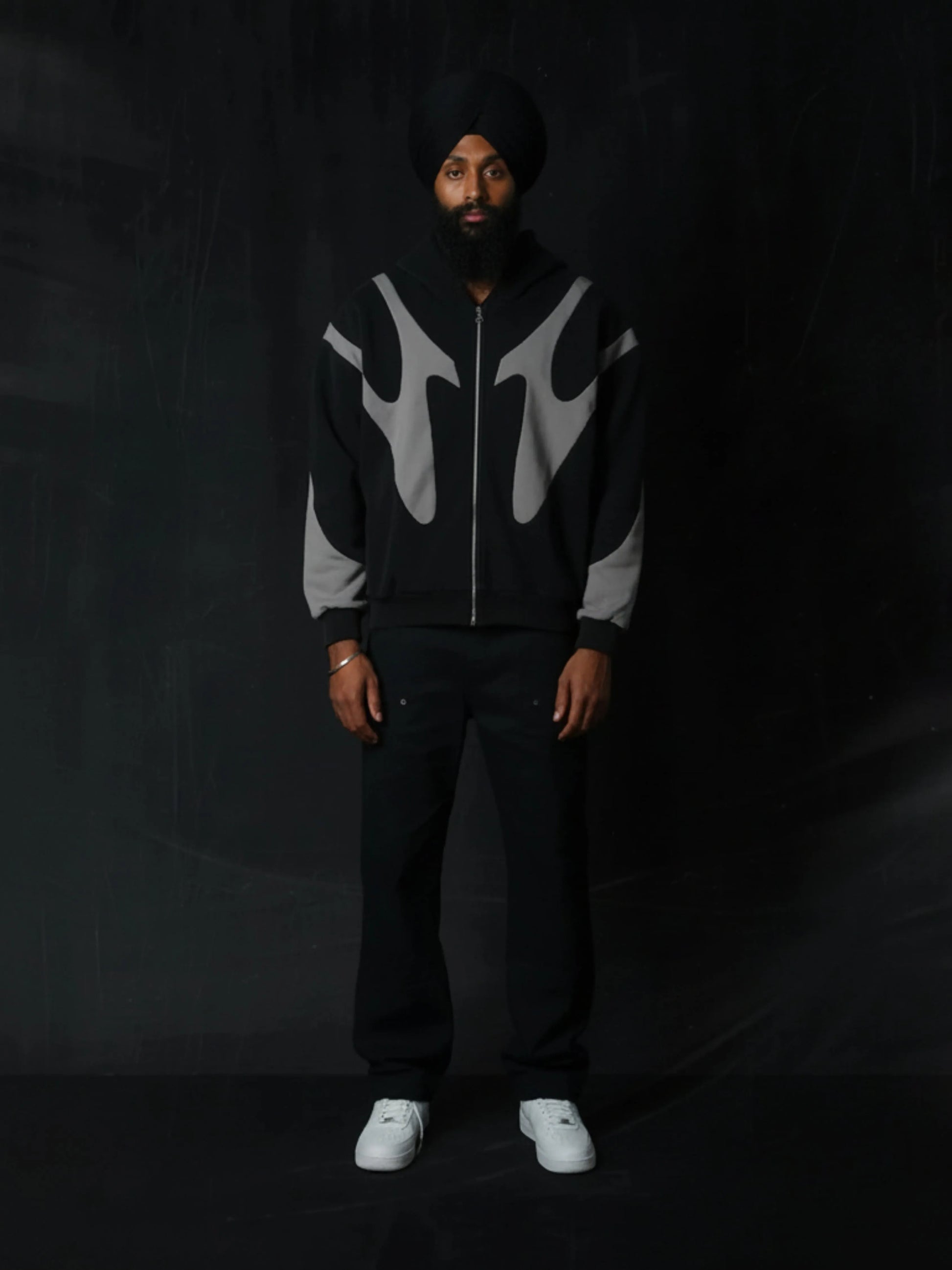 Person wearing a black and grey patterned hoodie with a dark background