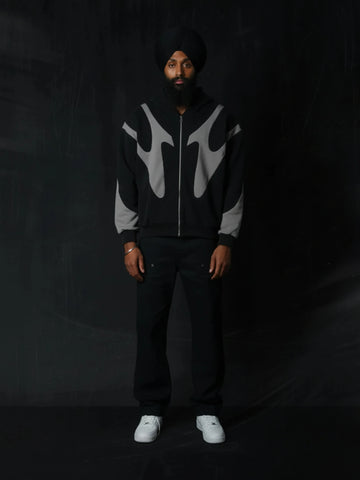 Person wearing a black and grey patterned hoodie with a dark background