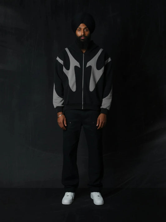 Person wearing a black and grey patterned hoodie with a dark background