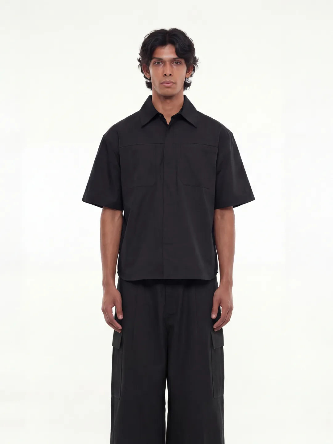 Person wearing a black shirt and pants on a white background