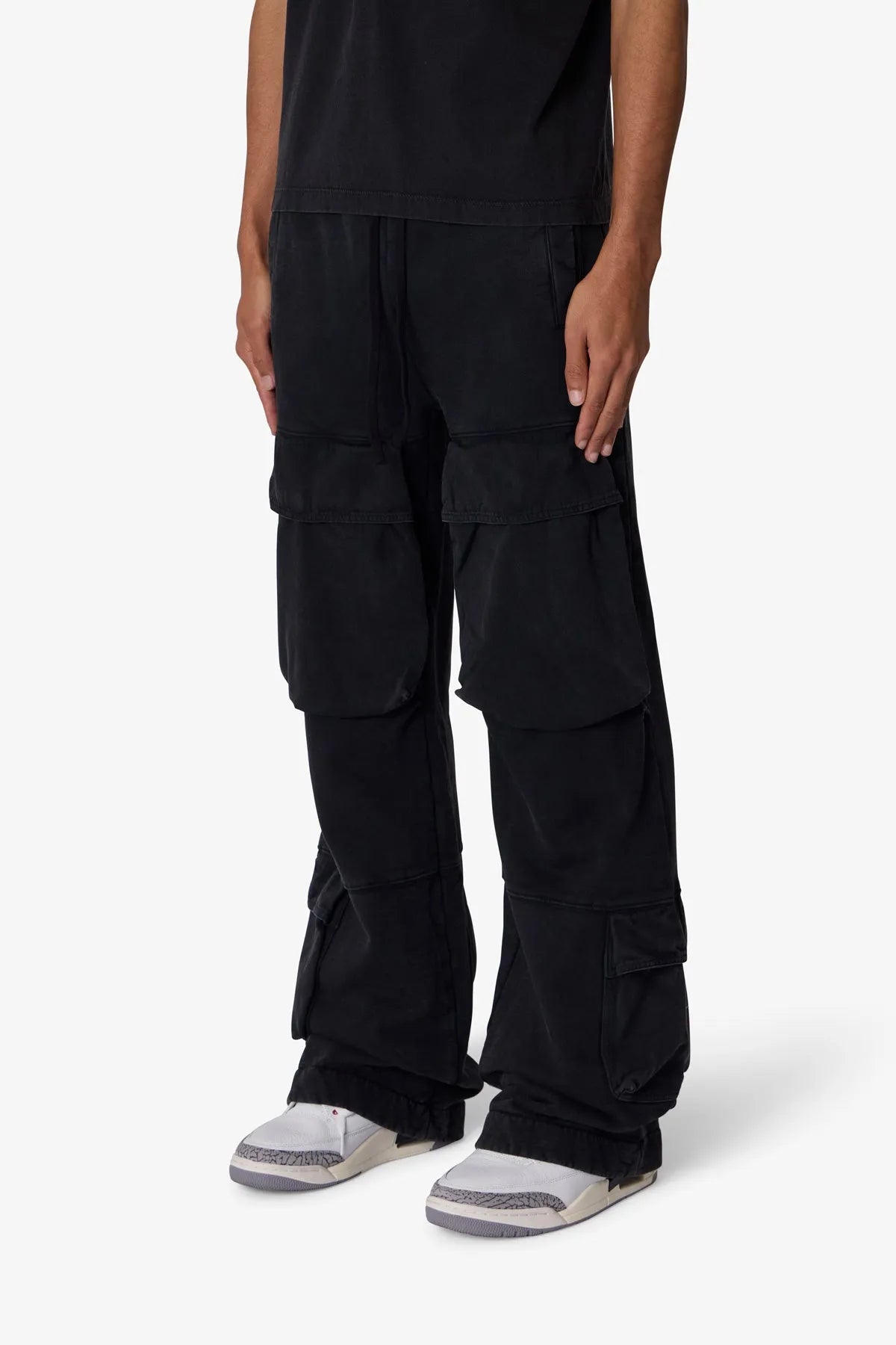 Person wearing black cargo pants on a white background