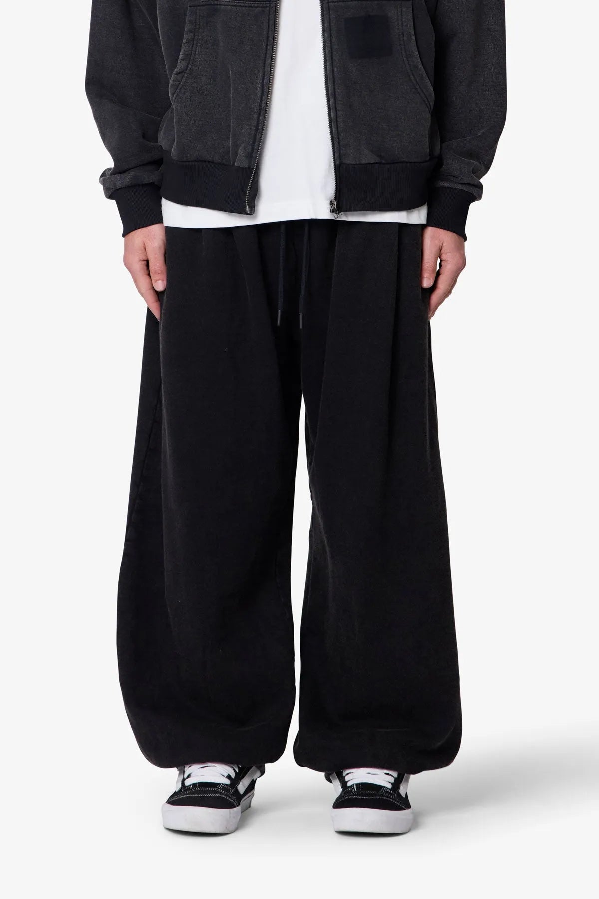 Person wearing black baggy sweatpants with a plain background