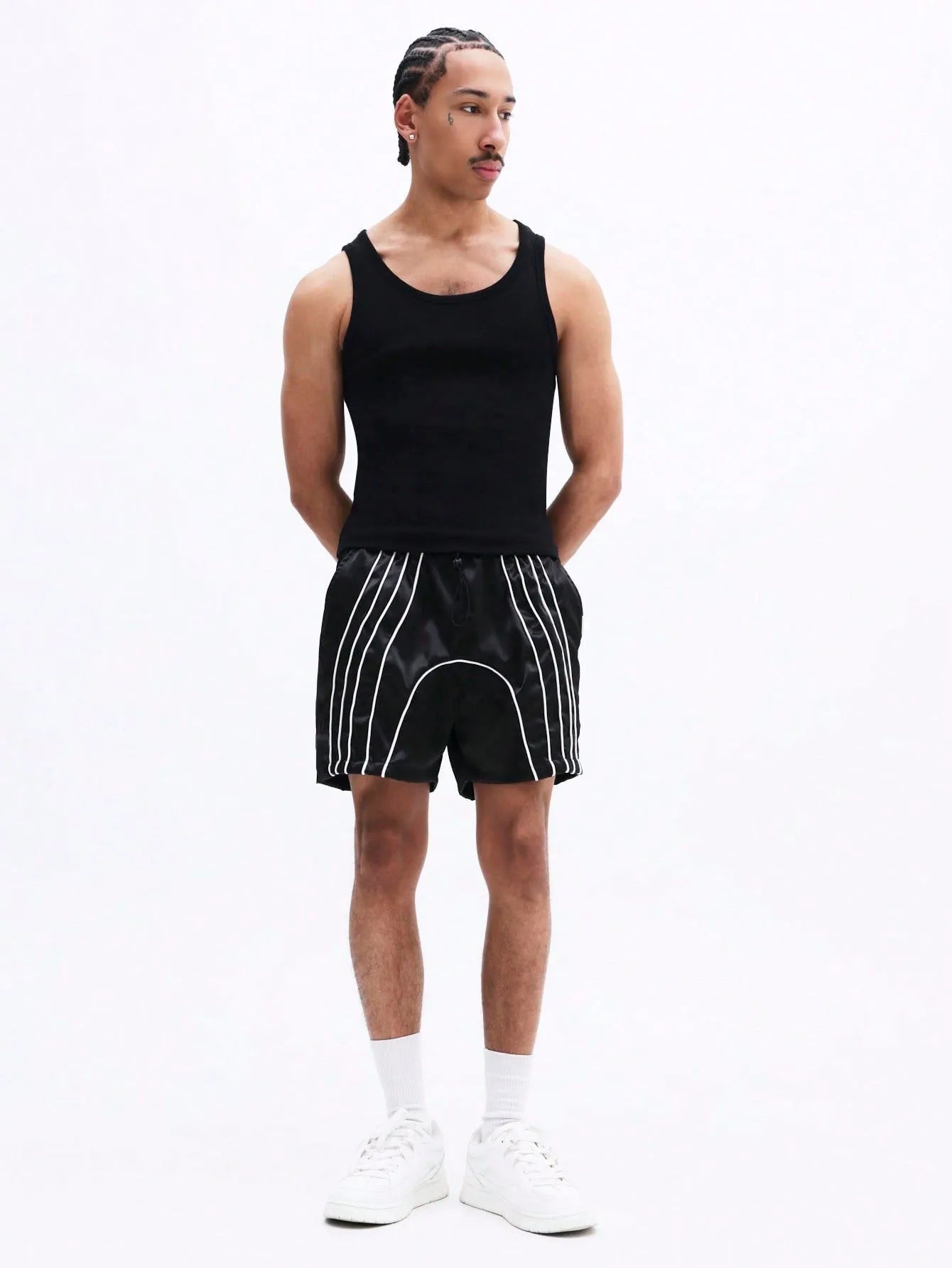 Black shorts with white stripes worn by a person on a plain background