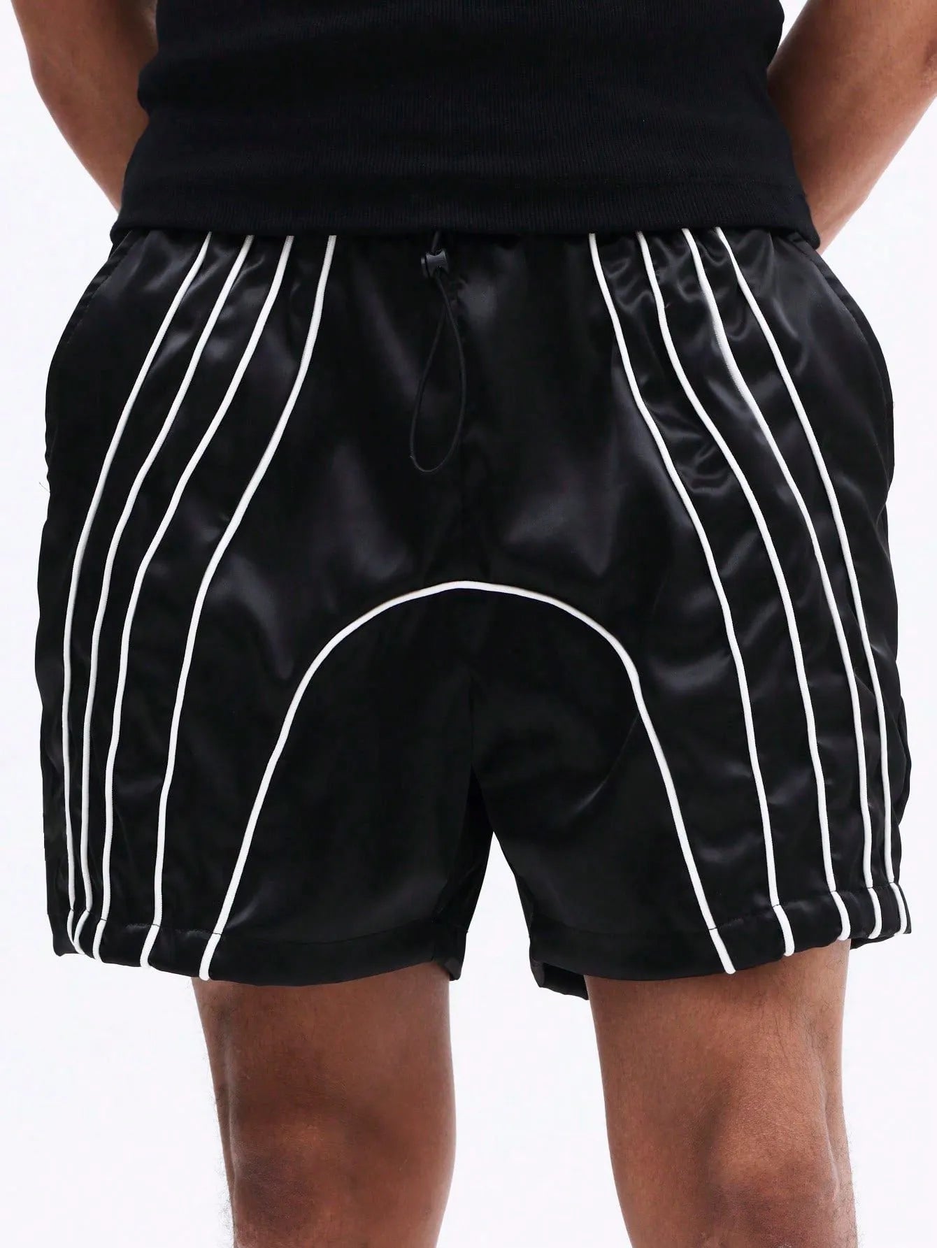Black shorts with white stripes worn by a person on a plain background