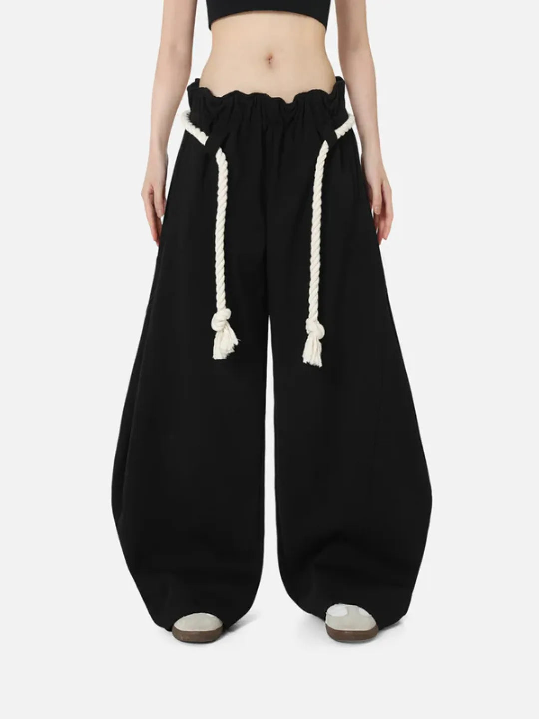 Black wide-leg sweatpants with white drawstrings worn by a person on a white background