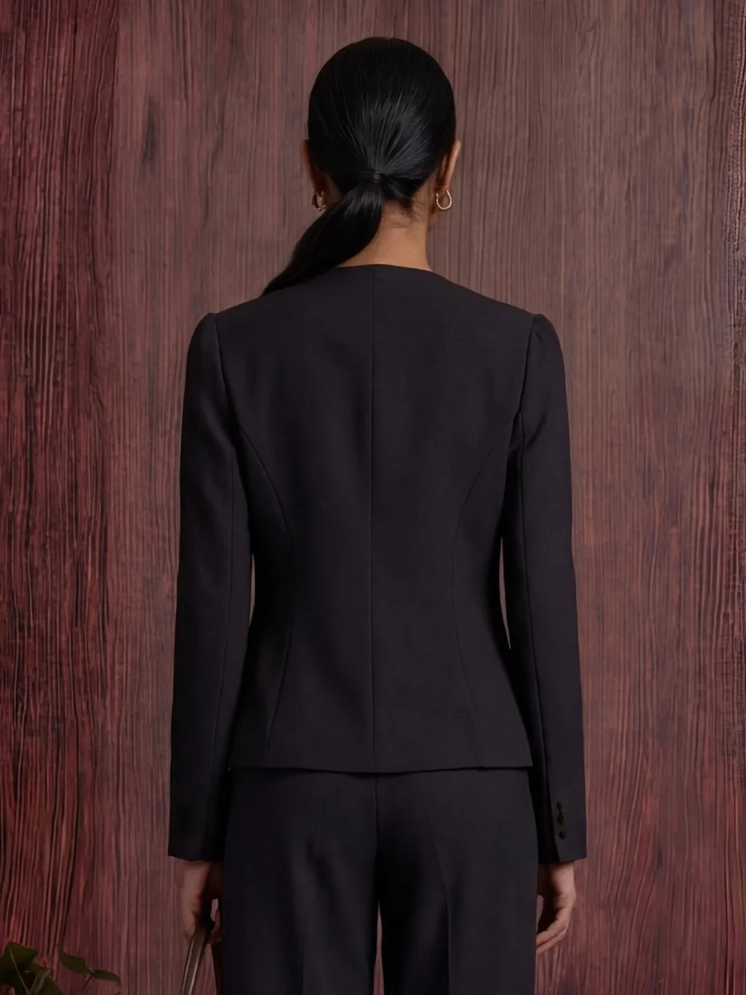 Person wearing a black blazer against a wooden background