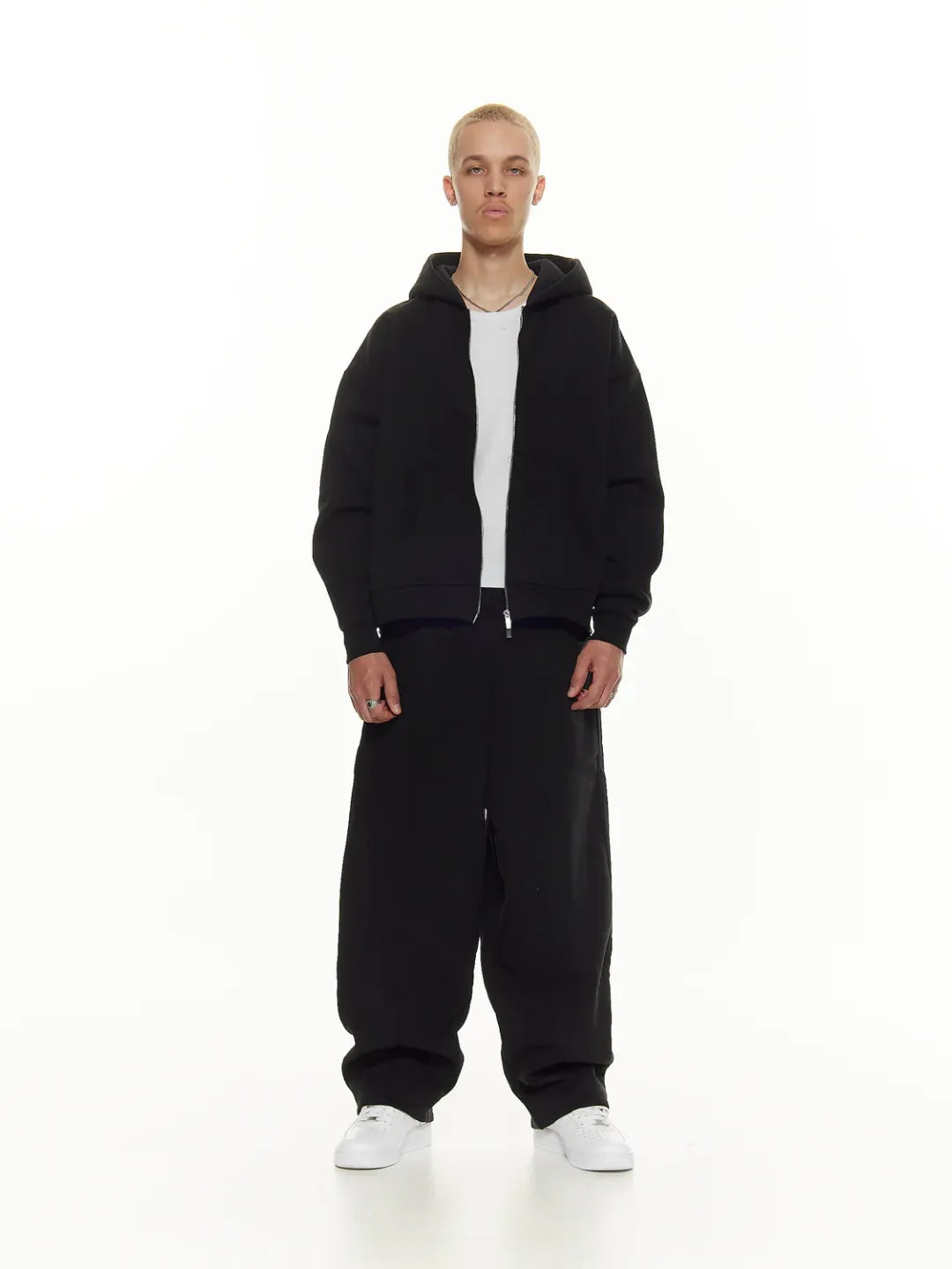 Person wearing a black zip-up jacket on a white background