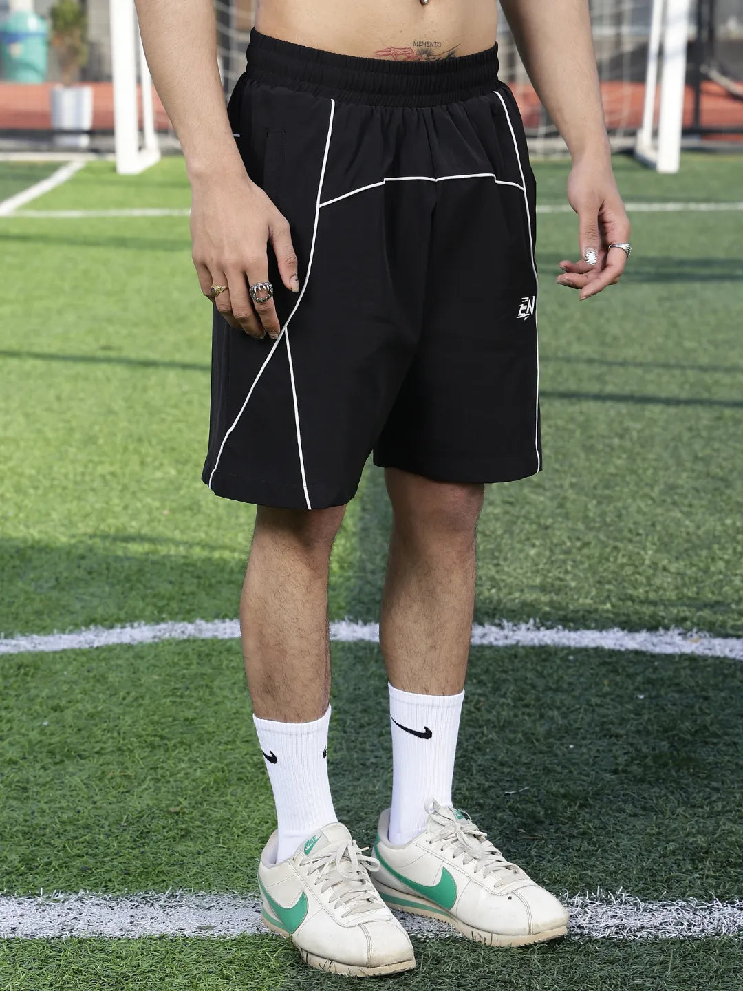 Person wearing black shorts with white lines on a sports field